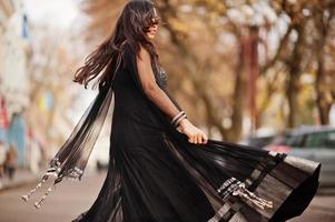 jolie fille indienne en robe saree noire posée en plein air dans la rue d'automne. photo