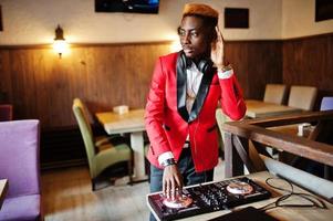 mode homme afro-américain modèle dj en costume rouge avec contrôleur dj. photo