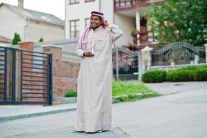 homme d'affaires arabe du moyen-orient posé dans la rue avec une coupe dorée à portée de main. photo