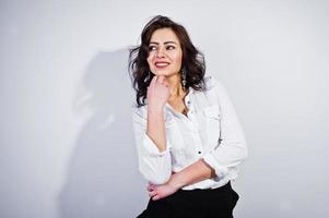 portrait en studio de jeune fille brune en blouse blanche sur fond blanc. photo