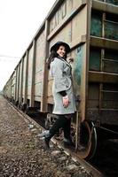 fille brune en manteau gris avec chapeau dans la gare. photo