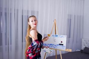 belle femme artiste peintre avec pinceaux et toile à l'huile posant lit dans la chambre. photo