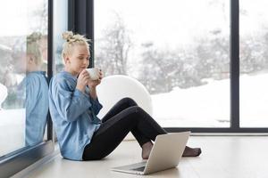 femme buvant du café et utilisant un ordinateur portable à la maison