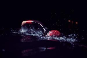 athlète de triathlon nageant dans la nuit noire portant une combinaison de plongée photo