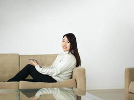 femme asiatique utilisant une tablette numérique sur un canapé photo