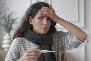 triste malade jeune femme italienne portant une écharpe tricotée autour du cou souffrant de rhume de grippe à la maison photo