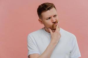 jeune homme ayant des doutes, regardant de côté et pensant photo