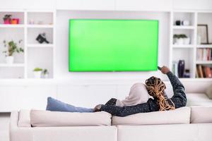 couple africain assis sur un canapé devant la télé ensemble photo