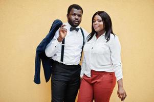 élégant couple afro-américain en tenue de soirée. couple romantique amoureux datant contre le mur jaune. photo