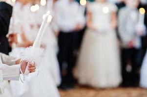 jeune fille en blanc tenir la bougie à la main à la première sainte communion. photo