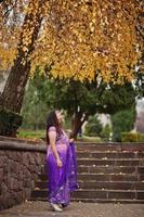 fille hindoue indienne au sari violet traditionnel posé dans la rue d'automne. photo