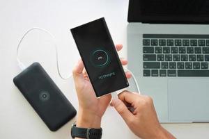 homme en gros plan tenant une batterie de charge de smartphone à partir d'un port de type c de banque d'alimentation avec utilisation de la technologie de charge pd. photo