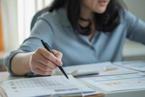 femme d'affaires tenant un stylo pour présenter les données de profit dans le graphique au superviseur via un ordinateur portable. photo