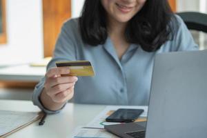 une femme utilise une carte de crédit pour effectuer des achats en ligne sur son ordinateur portable. concept de dépenses par carte de crédit photo