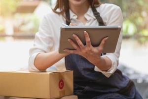 jeune femme d'affaires utilisant une tablette pour vérifier les ventes de produits en ligne
