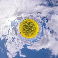 transformation de la petite planète du panorama sphérique à 360 degrés. vue aérienne abstraite sphérique dans le champ de colza avec de beaux nuages impressionnants. courbure de l'espace. photo