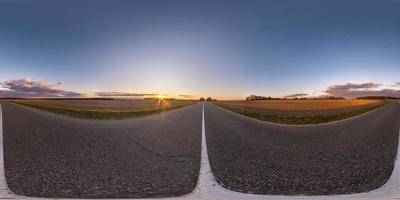 panorama hdri sphérique complet sans couture vue à 360 degrés sur une route asphaltée sans circulation entre les champs le soir avant le coucher du soleil avec un ciel clair. Panorama 360 en projection équirectangulaire, contenu vr ar photo