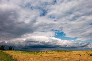 panorama hdr sur route goudronnée parmi les champs en soirée avec de superbes nuages noirs avant la tempête photo