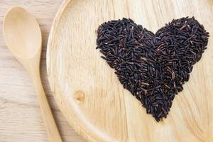 baie de riz coeur dans des bols en bois avec cuillère sur fond en bois. concept photo