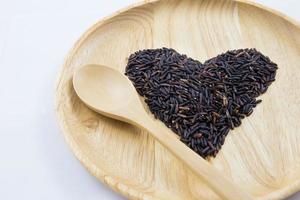 baie de riz coeur dans des bols en bois avec cuillère sur fond en bois. concept photo