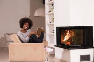 femme noire lisant un livre devant la cheminée photo