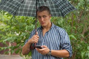 homme avec parapluie et téléphone portable photo