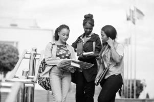 trois étudiantes africaines ont posé avec des sacs à dos et des articles scolaires dans la cour de l'université. photo