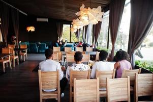 amis africains heureux assis, bavardant au café et mangeant de la nourriture. groupe de peuples noirs se réunissant au restaurant et dînant. photo