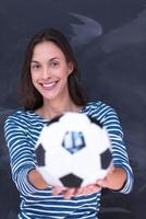 femme tenant un ballon de football devant une planche à dessin à la craie photo