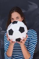 femme tenant un ballon de football devant une planche à dessin à la craie photo