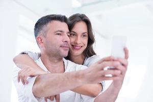 couple heureux utilisant un téléphone portable à la maison photo