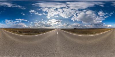 panorama sphérique complet sans couture vue à 360 degrés sur une route asphaltée sans circulation parmi les champs au printemps avec un ciel nuageux. Panorama 360 en projection équirectangulaire, contenu vr ar photo