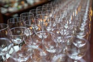 beaucoup de verres vides sur la table de réception. gros plan sur une rangée de verres se préparent au service pour le dîner photo