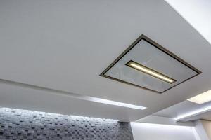 lampes halogènes sur plafond suspendu et construction de cloisons sèches dans une pièce vide d'un appartement ou d'une maison. plafond tendu de forme blanche et complexe. photo