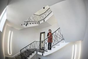 la petite femme reste dans un immense hall avec escalier d'urgence et sortie d'évacuation. grand angle photo