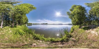 panorama hdri sphérique harmonieux vue d'angle à 360 degrés sur la côte d'herbe d'un petit lac ou d'une rivière en été ensoleillé avec de beaux nuages dans le ciel bleu en projection équirectangulaire, contenu vr photo