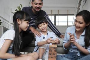 joyeuse activité familiale thaïlandaise asiatique, parents, papa, maman et enfants s'amusent à jouer et de joyeux blocs de jouets en bois ensemble sur le sol du salon, le week-end de loisirs et le style de vie de bien-être domestique.