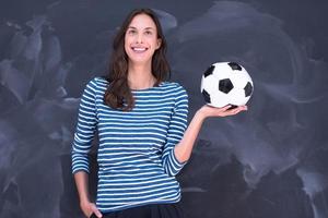 femme tenant un ballon de football devant une planche à dessin à la craie photo