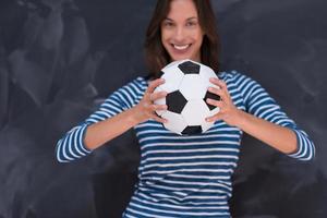 femme tenant un ballon de football devant une planche à dessin à la craie photo