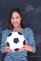 femme tenant un ballon de football devant une planche à dessin à la craie photo