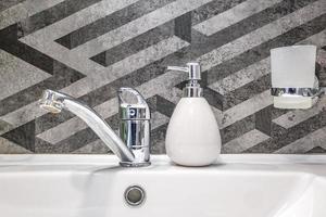 distributeurs de savon et de shampoing près d'un lavabo en céramique avec robinet dans une salle de bain ou une cuisine loft coûteuse photo