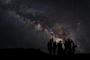 paysage avec voie lactée, ciel nocturne avec étoiles et silhouette de gens heureux debout sur la montagne, photographie longue exposition, avec grain photo