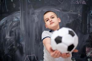 garçon heureux tenant un ballon de football devant le tableau photo