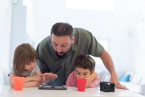 père célibataire à la maison avec deux enfants jouant à des jeux sur tablette photo