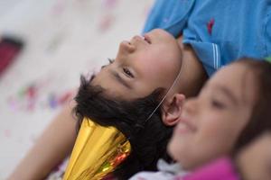 enfants soufflant des confettis allongés sur le sol photo