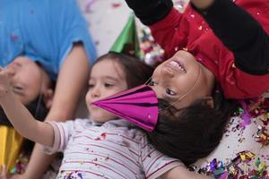 enfants soufflant des confettis allongés sur le sol photo