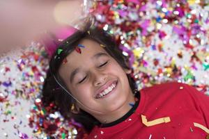 enfant soufflant des confettis allongé sur le sol photo