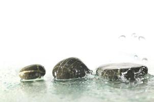 pierres zen humides isolées avec des éclaboussures de gouttes d'eau photo