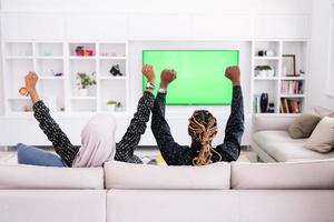 couple africain assis sur un canapé devant la télé ensemble photo