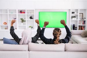 couple africain assis sur un canapé devant la télé ensemble photo